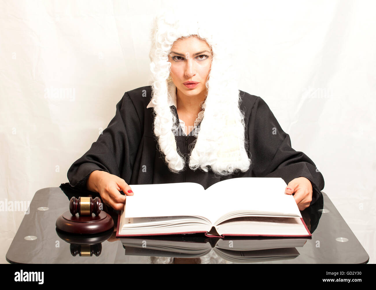 Femme juge porter une perruque et manteau noir avec le juge gavel et livre sur fond blanc Banque D'Images