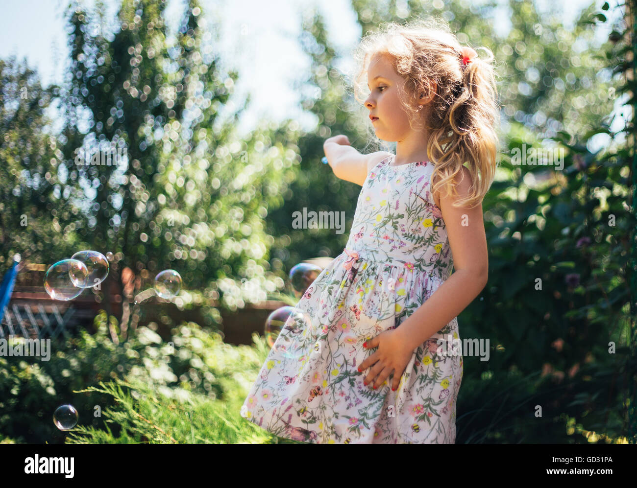 Cute little girl est un souffle des bulles de savon et d'avoir du plaisir Banque D'Images