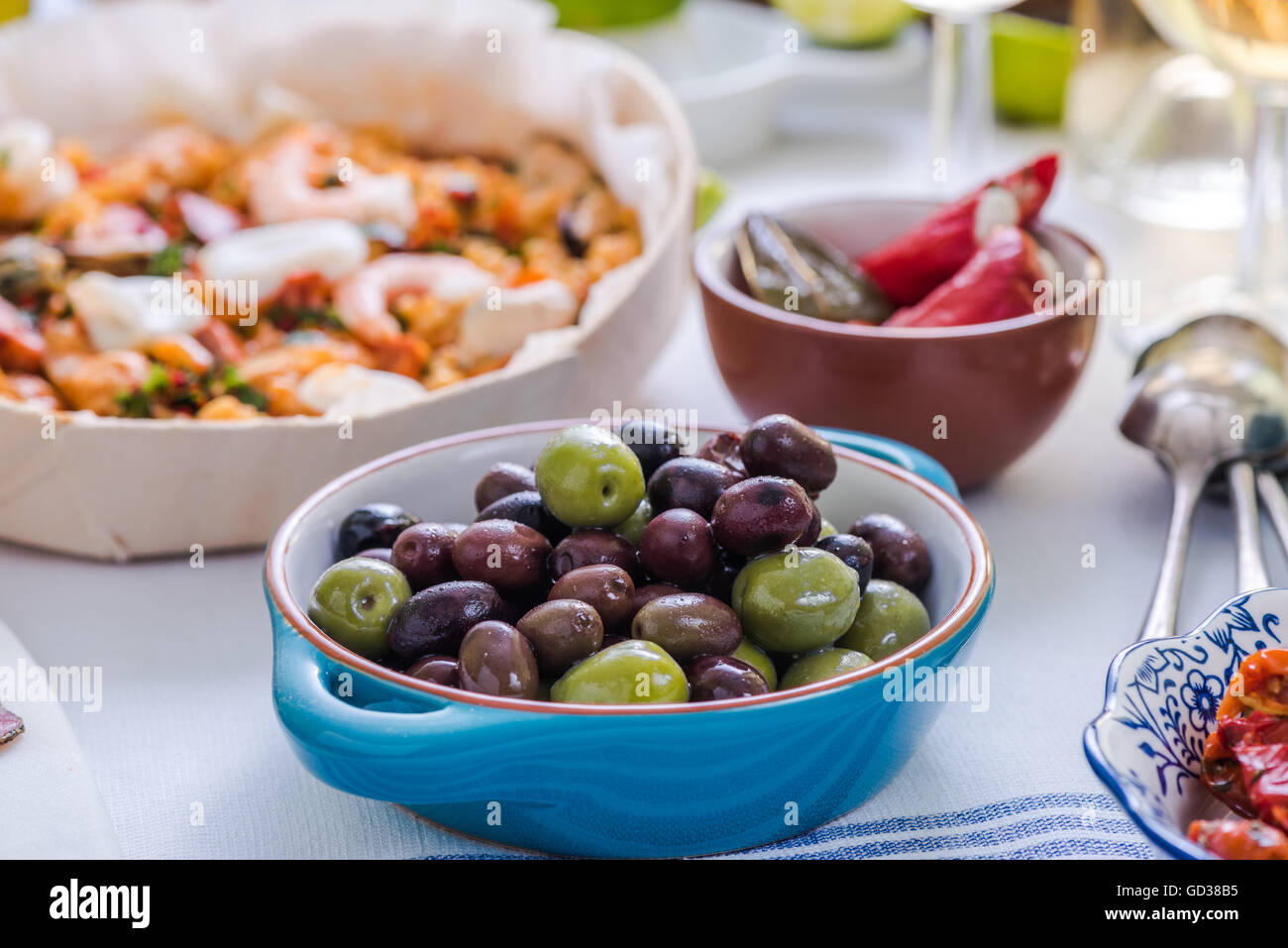 Olives fraîches et paella en arrière-plan, le partage de nourriture sur la table Banque D'Images