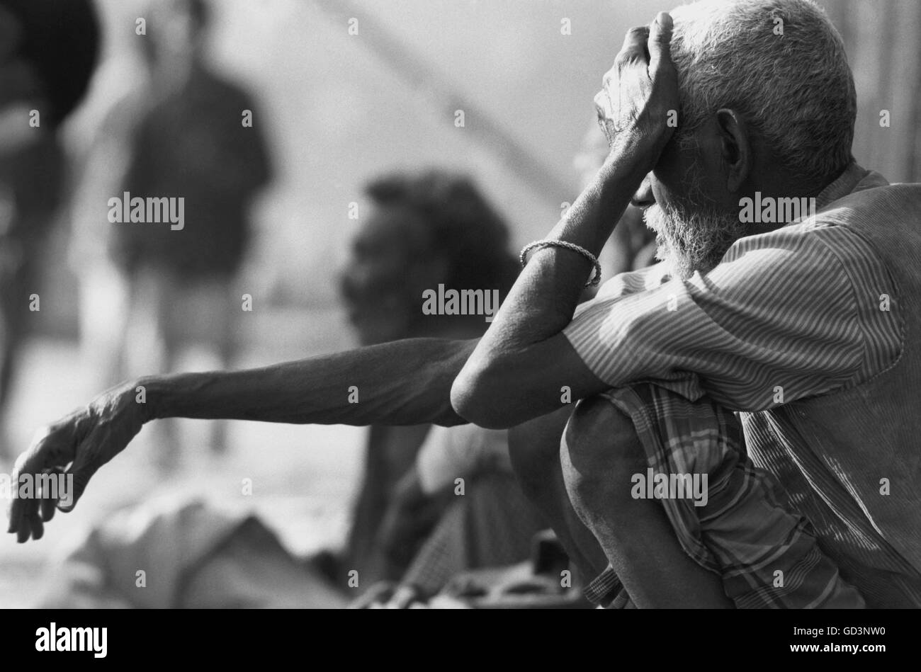 Un vieil homme assis sur une rue Banque D'Images