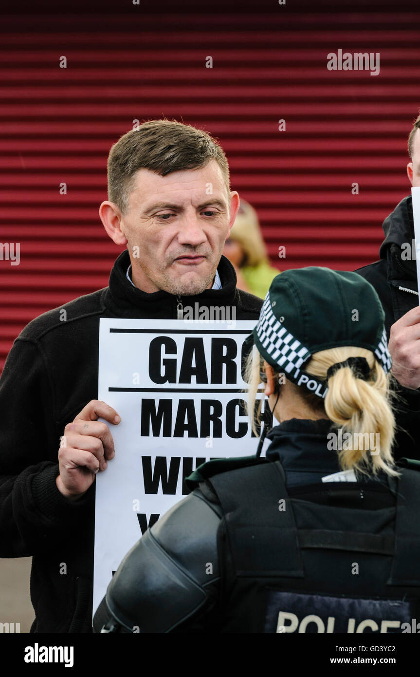 Belfast, Irlande du Nord. 12 juil 2016 - un manifestant de la Grande Ardoyne collectif résidents (GARC) est titulaire d'une bannière disant 'March où vous êtes bienvenue' et regarde une femme agent de police. Crédit : Stephen Barnes/Alamy Live News Banque D'Images