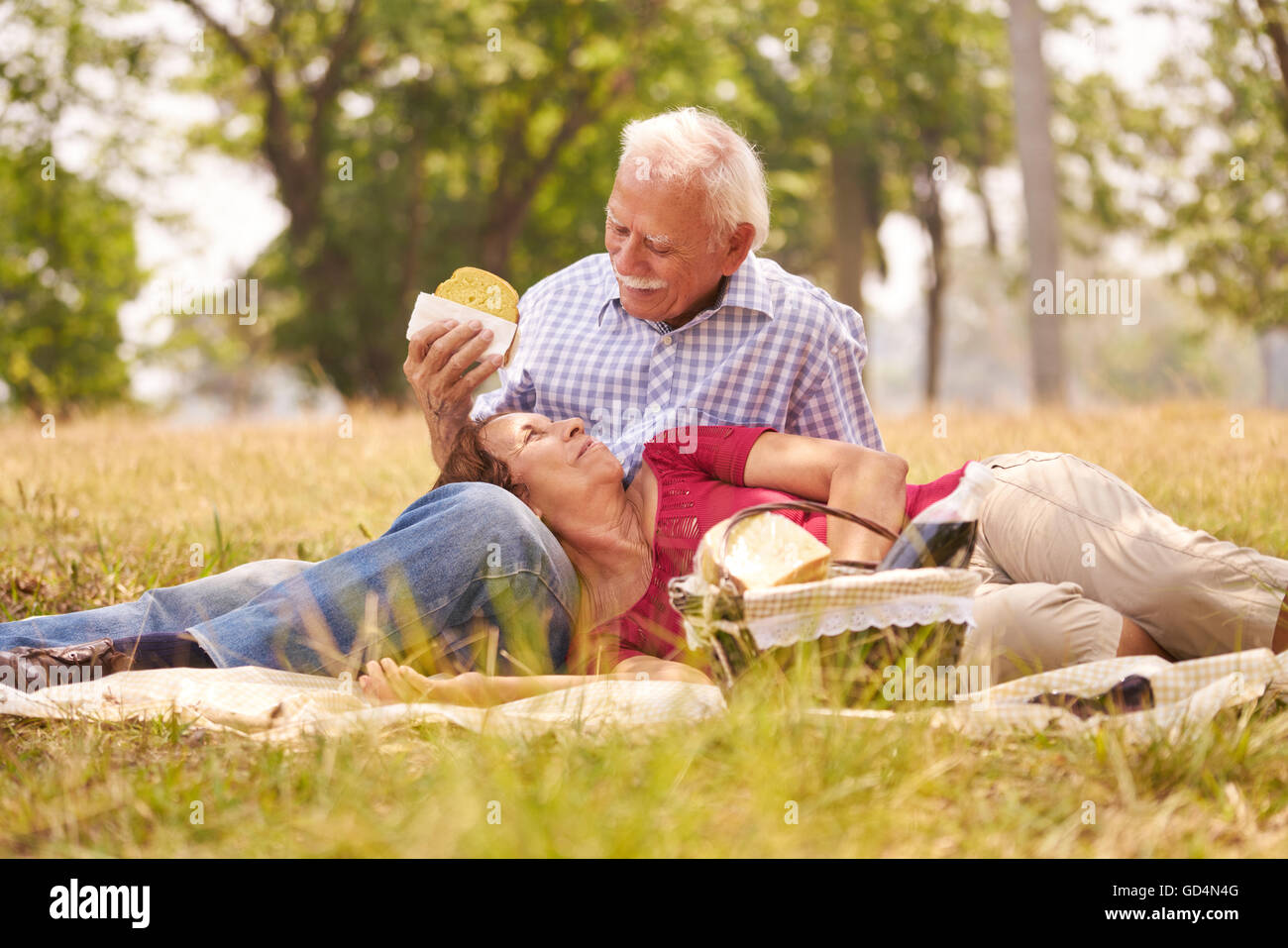 Les personnes âgées, en couple, une femme et un homme âgés en parc. Les aînés retraités de manger des aliments au picnic Banque D'Images