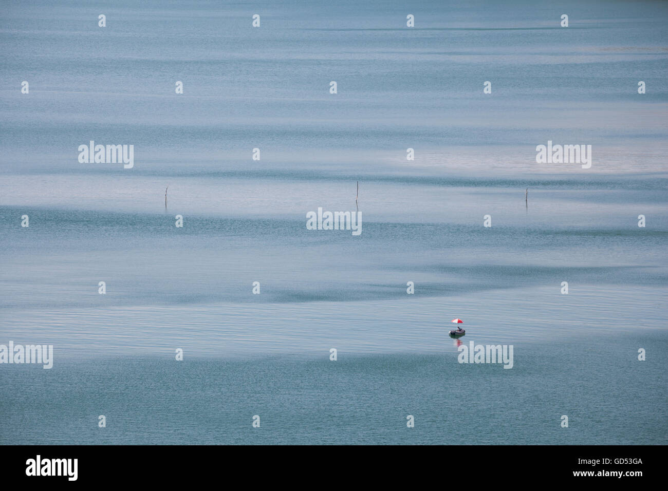 Lonely annexe gonflable Bateau avec moteur hors-bord et parasol, ancrée dans une baie de la mer dans une chaude journée d'été. Banque D'Images