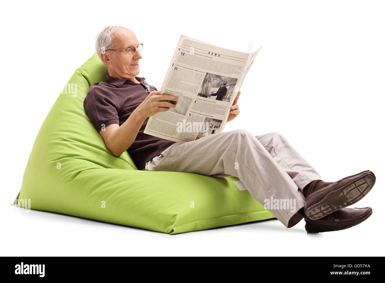 Senior joyeuse lire un journal assis sur un confortable fauteuil poire verte isolée sur fond blanc Banque D'Images
