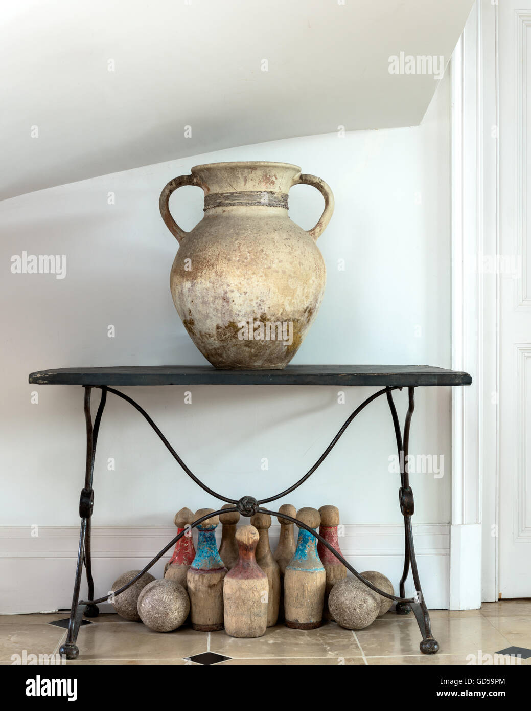Grande pierre urne sur la table en fer. Sous la table d'un jeu de quilles en bois vintage Banque D'Images
