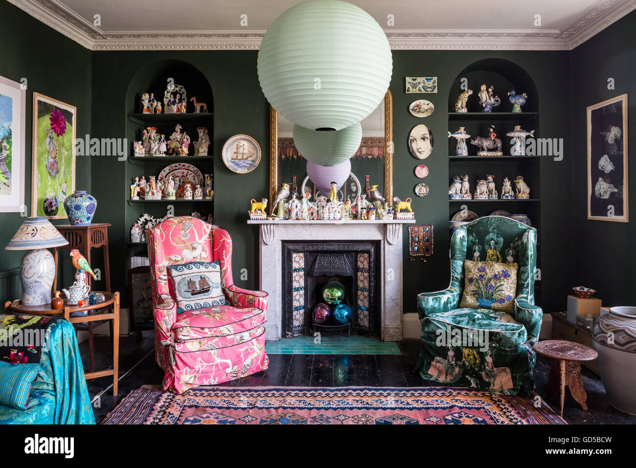 Grand kilims et un assortiment éclectique d'art dans la salle de dessin peint en vert Sherwood par Farrow & Ball. Les plaques d'Fornasettie Banque D'Images
