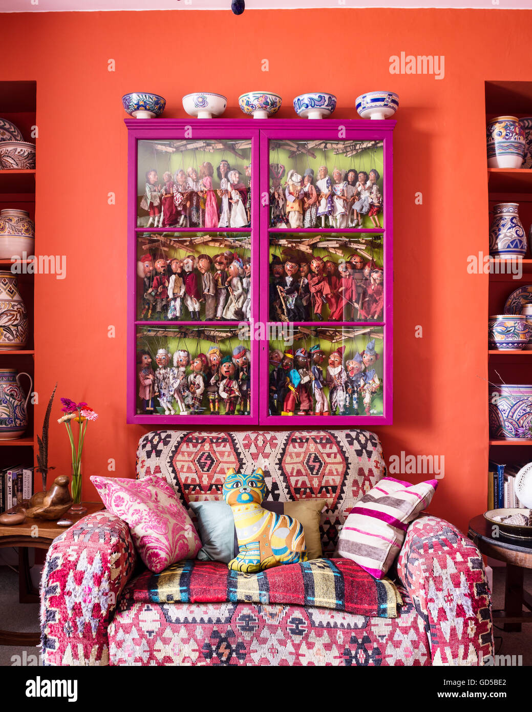 Canapé club capitonnées de matériau kilim sous une façade de verre contenant du cabinet rose collection de marionnettes marionnette. Banque D'Images