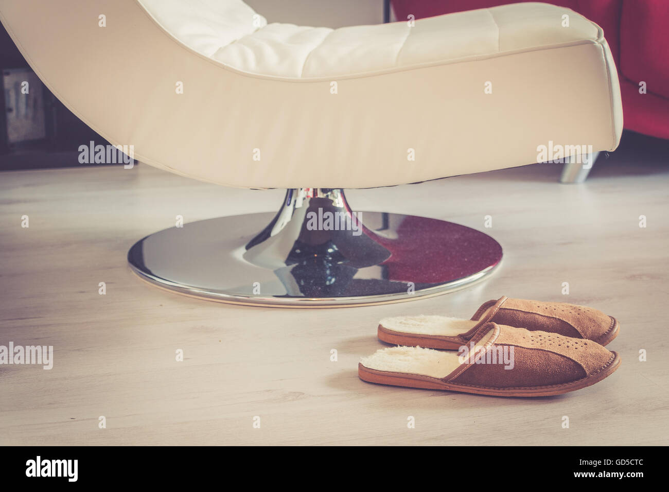 La laine marron chaussons confortables en face de chaise de salon sur plancher en bois gris dans la salle de séjour Banque D'Images