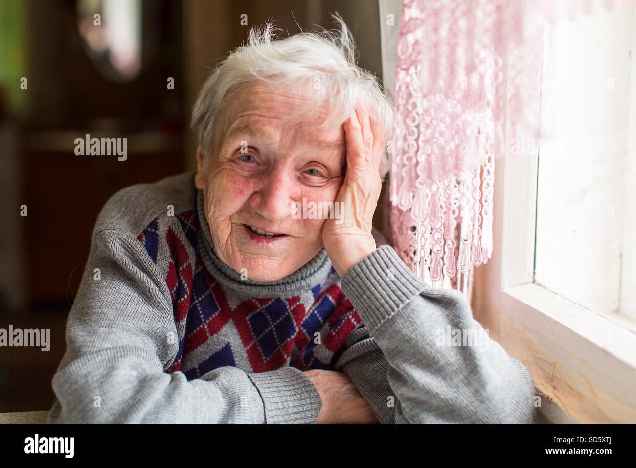 Bonne femme âgée assise à table, portrait. Banque D'Images
