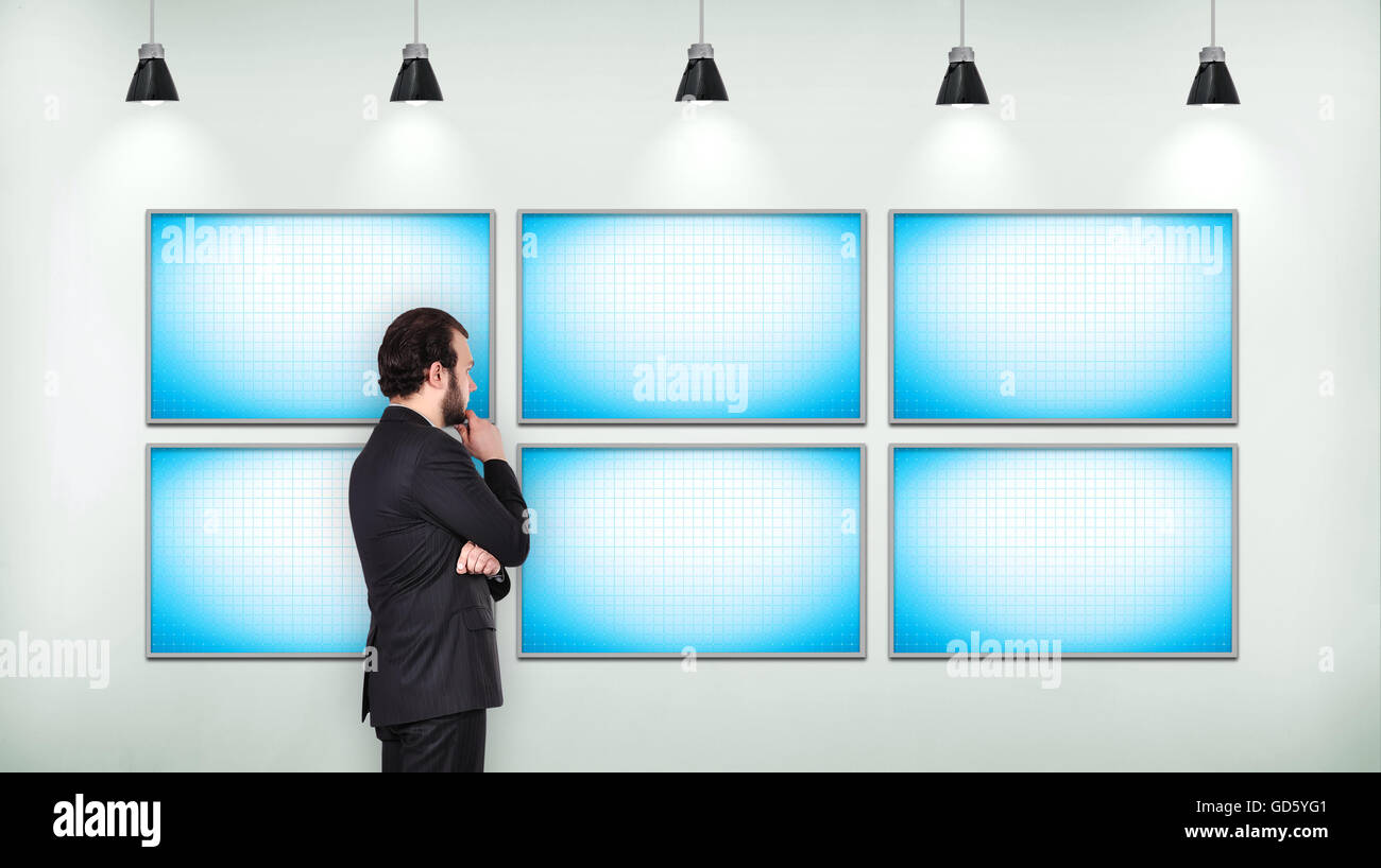 Businessman à vide sur l'écran tv six sur mur de béton en loft Banque D'Images