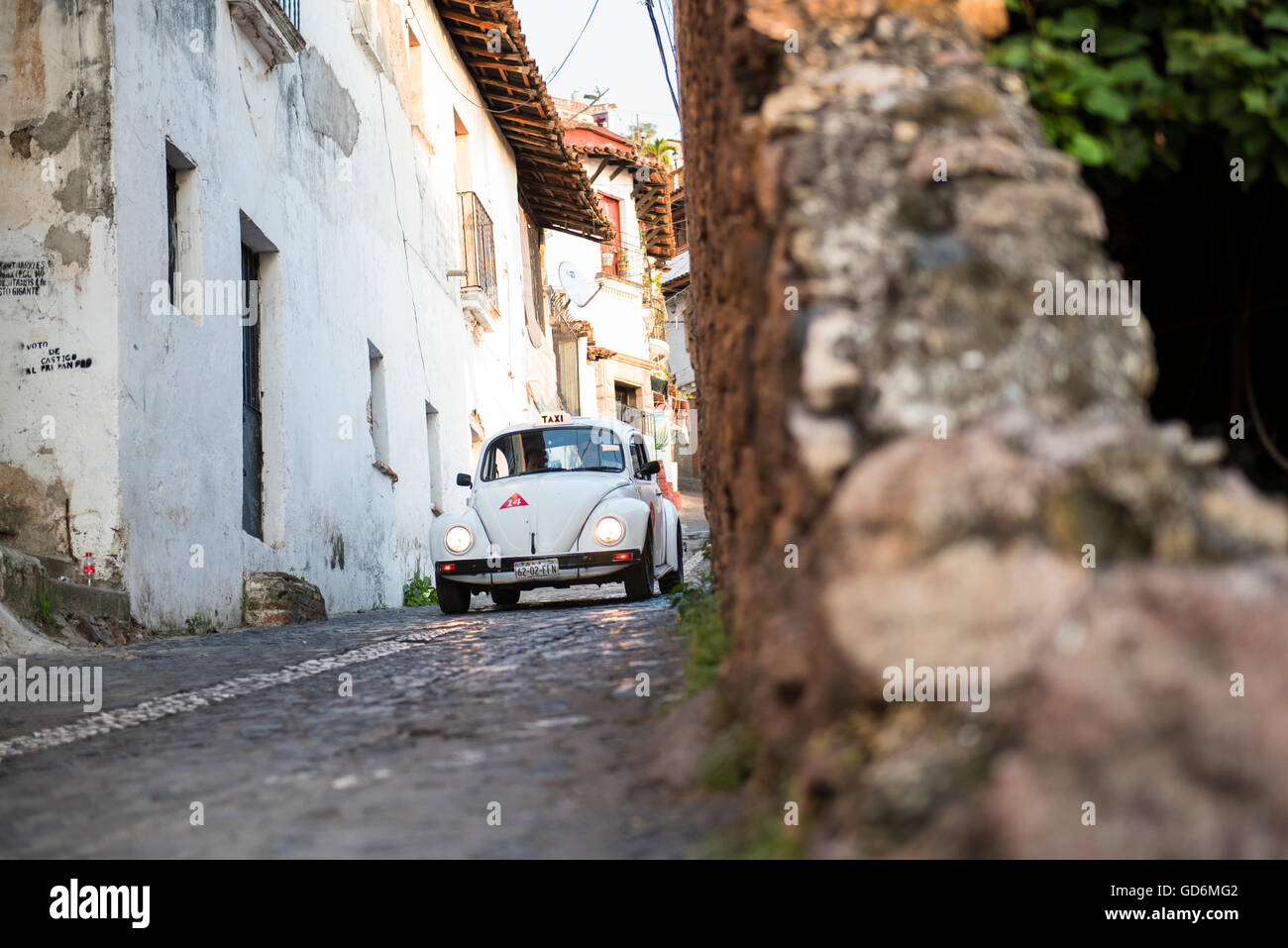 Une coccinelle Volkswagen classic cruises les rues pavées de Taxco, Guerrero, Mexique. Banque D'Images