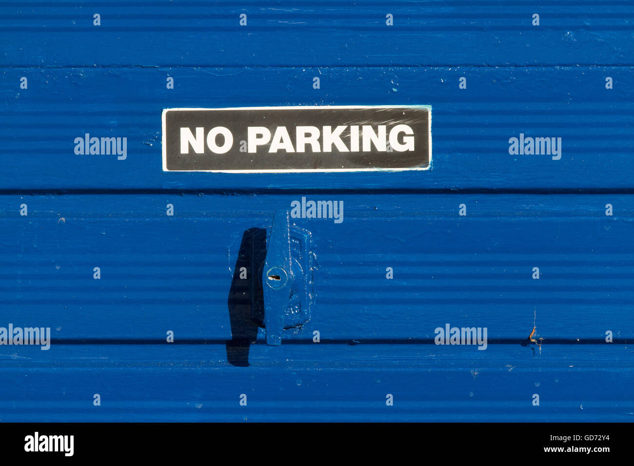 No Parking sign on a bright blue metal porte de garage. Banque D'Images