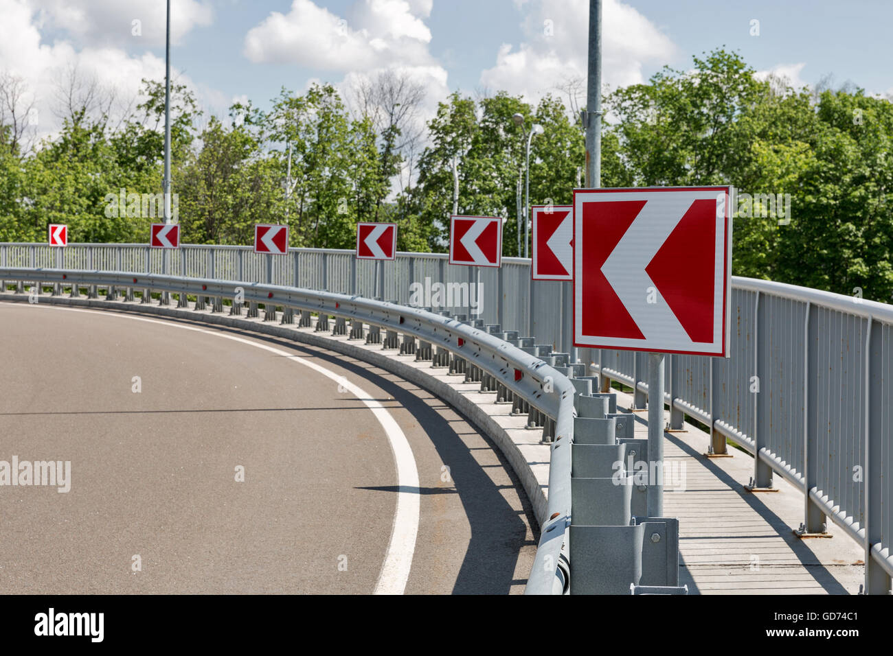 Les flèches blanches sur le rouge de la signalisation routière, indiquant un long virage à gauche Banque D'Images