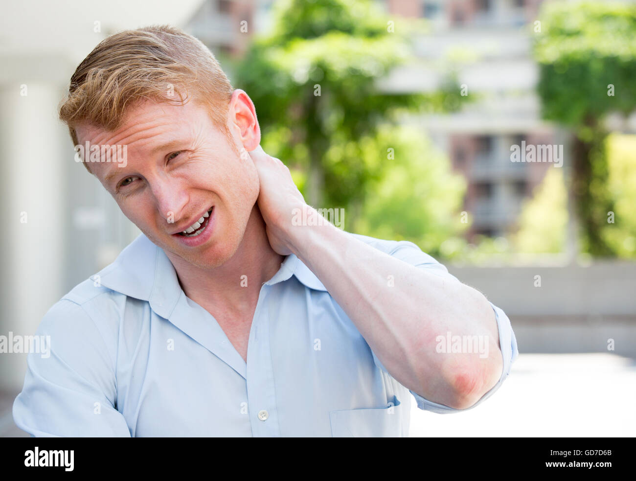Closeup portrait, jeune homme en chemise bleue avec une douleur au cou dans la vertèbre thoracique après de longues heures de travail et études Banque D'Images