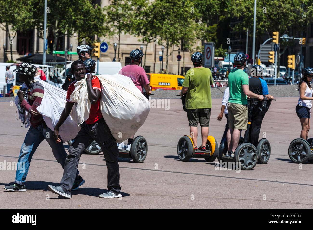 Deux vendeurs noire transportant des marchandises dans un sac appelé manteros entre les touristes sur un Segway dans le centre de Barcelone Banque D'Images
