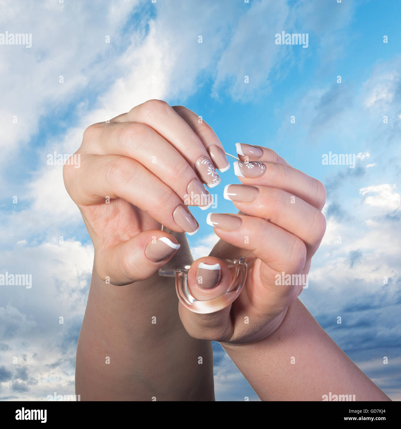 Les mains avec French manucure classique tenir un verre tasse contre le ciel bleu Banque D'Images
