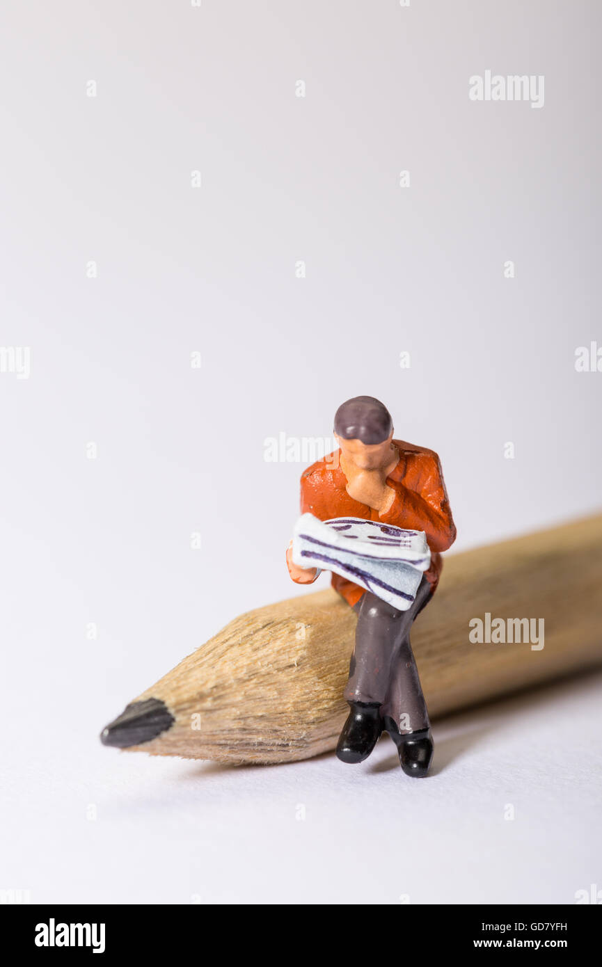 Notion de droit d'une figure masculine à l'intermédiaire d'un journal assis sur un crayon à à un jeu de mots croisés ou à la recherche d'un emploi Banque D'Images Notion de droit d'une figure masculine à l'intermédiaire d'un journal assis sur un crayon à à un jeu de mots croisés ou à la recherche d'un emploi Banque D'Images