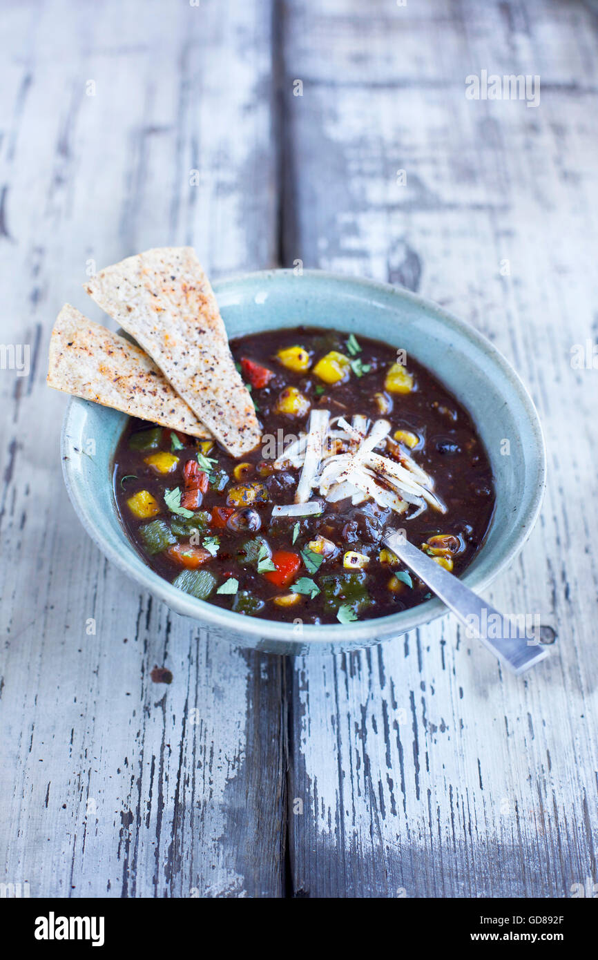 Soupe de haricots noirs avec des poivrons rôtis et cilanrto on a rustic white/fond de bois tourné à partir de la vue de face. Banque D'Images