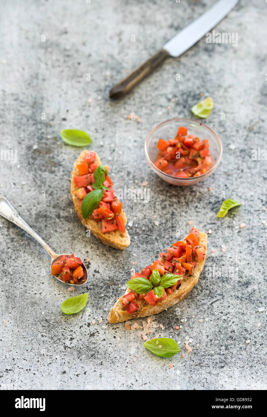 Deux canapés aux tomates et basilic, servi avec cuillère et couteau sur fond de béton, vue du dessus, la composition verticale Banque D'Images