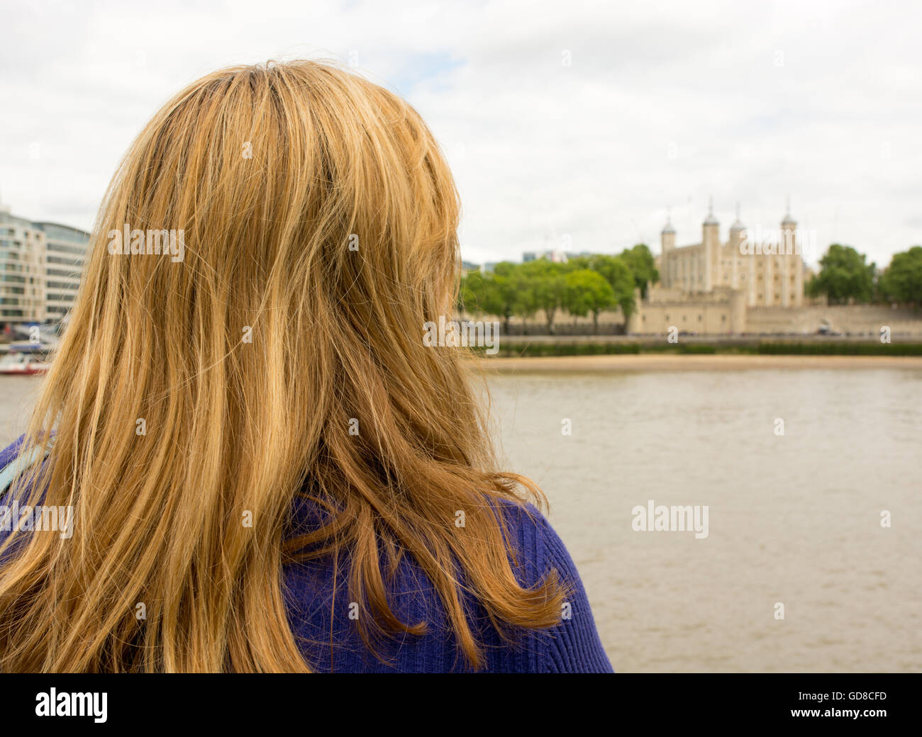 Femme aux cheveux blonds à la recherche de l'autre côté de la Tamise jusqu'à la Tour de Londres. Banque D'Images