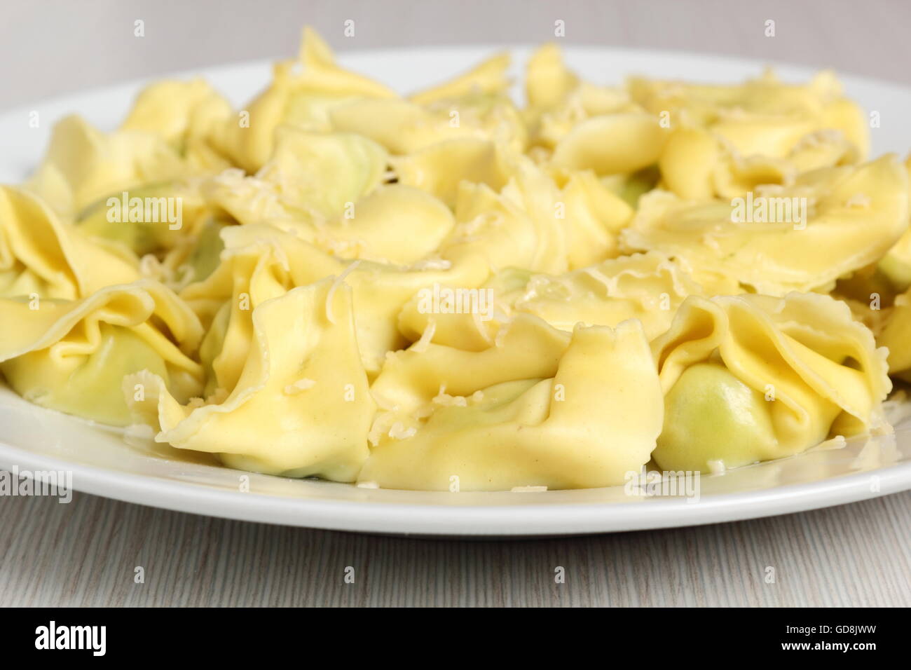 Tortellini farci aux épinards et ricotta. Recouvert de fromage râpé. Banque D'Images