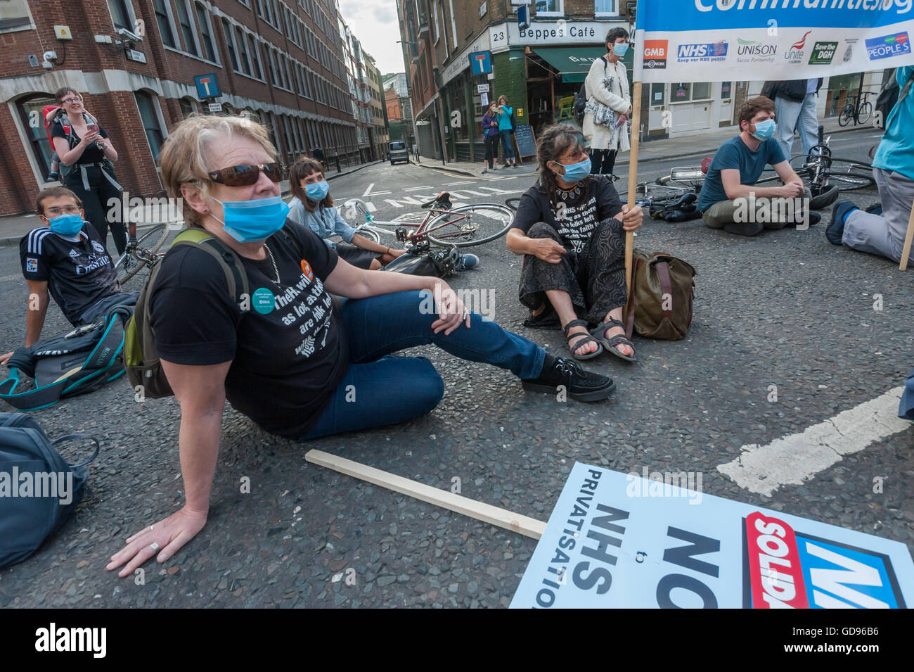 Londres, Royaume-Uni, le 14 juillet 2016. Les travailleurs de la santé et de supports dédiés à la sauvegarde d'un système public, livré et responsable NHS mis sur les masques chirurgicaux et s'asseoir à l'extérieur de St Bartholomew's Hospital avant leur courte mars derrière le feu de moteur FBU de St Paul. L'événement était organisé par la solidarité du NHS. Peter Marshall/Alamy Live News Banque D'Images