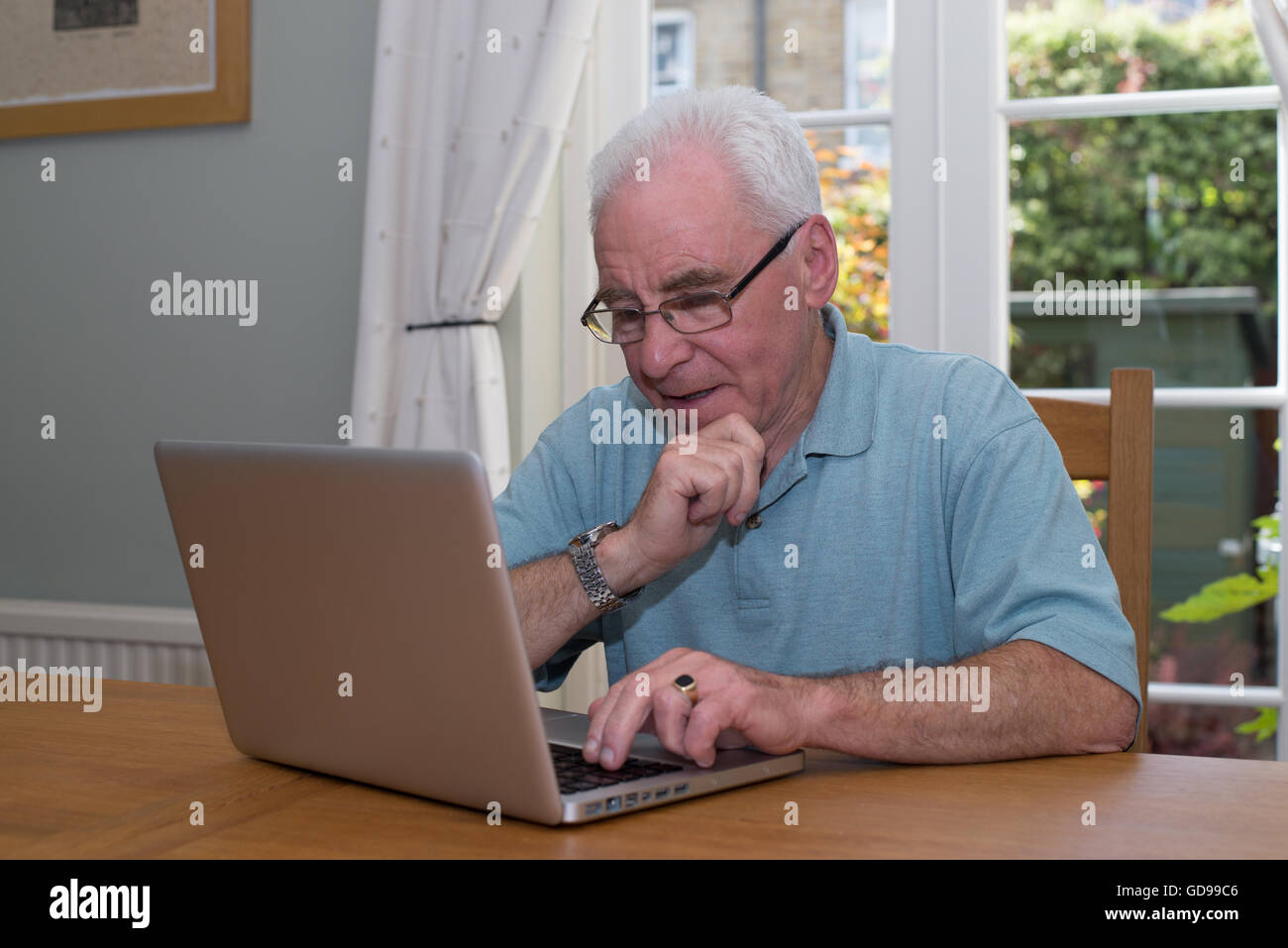 Vieil homme est assis à une table à l'aide d'un ordinateur portable Banque D'Images