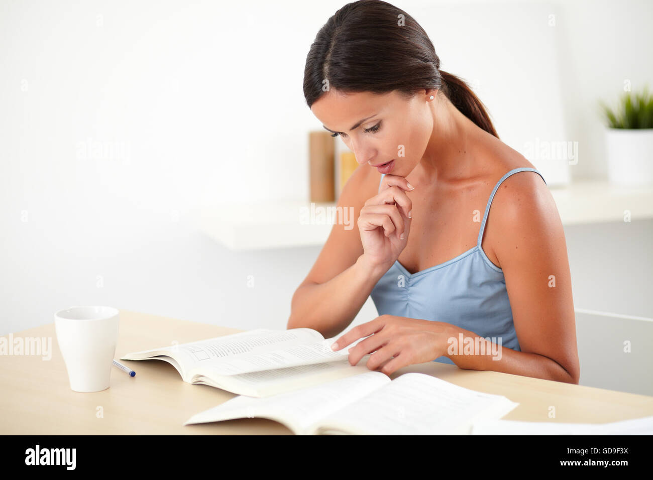 Chemisier femme sophistiquée dans l'élégant quartier de penser tout en lisant un livre à piscine Banque D'Images