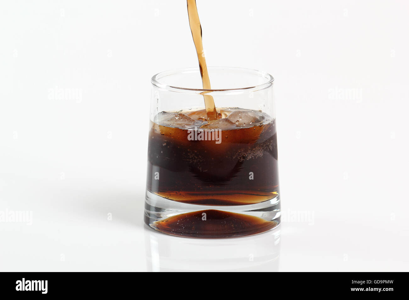 Pouring cola dans un verre avec des glaçons. Isolé sur fond blanc. Banque D'Images