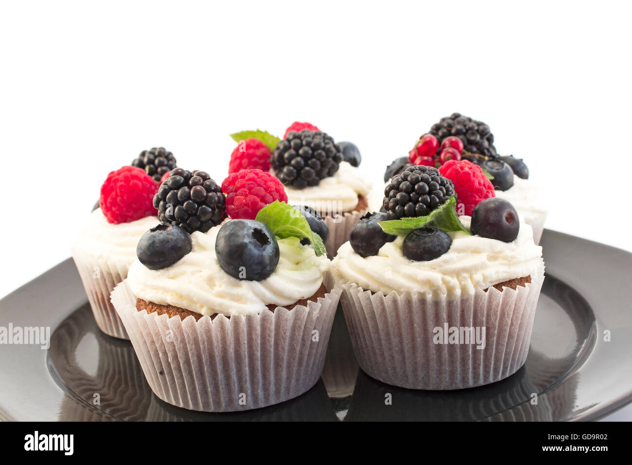 Cupcakes aux fruits rouges élégants sur la plaque noire. Banque D'Images