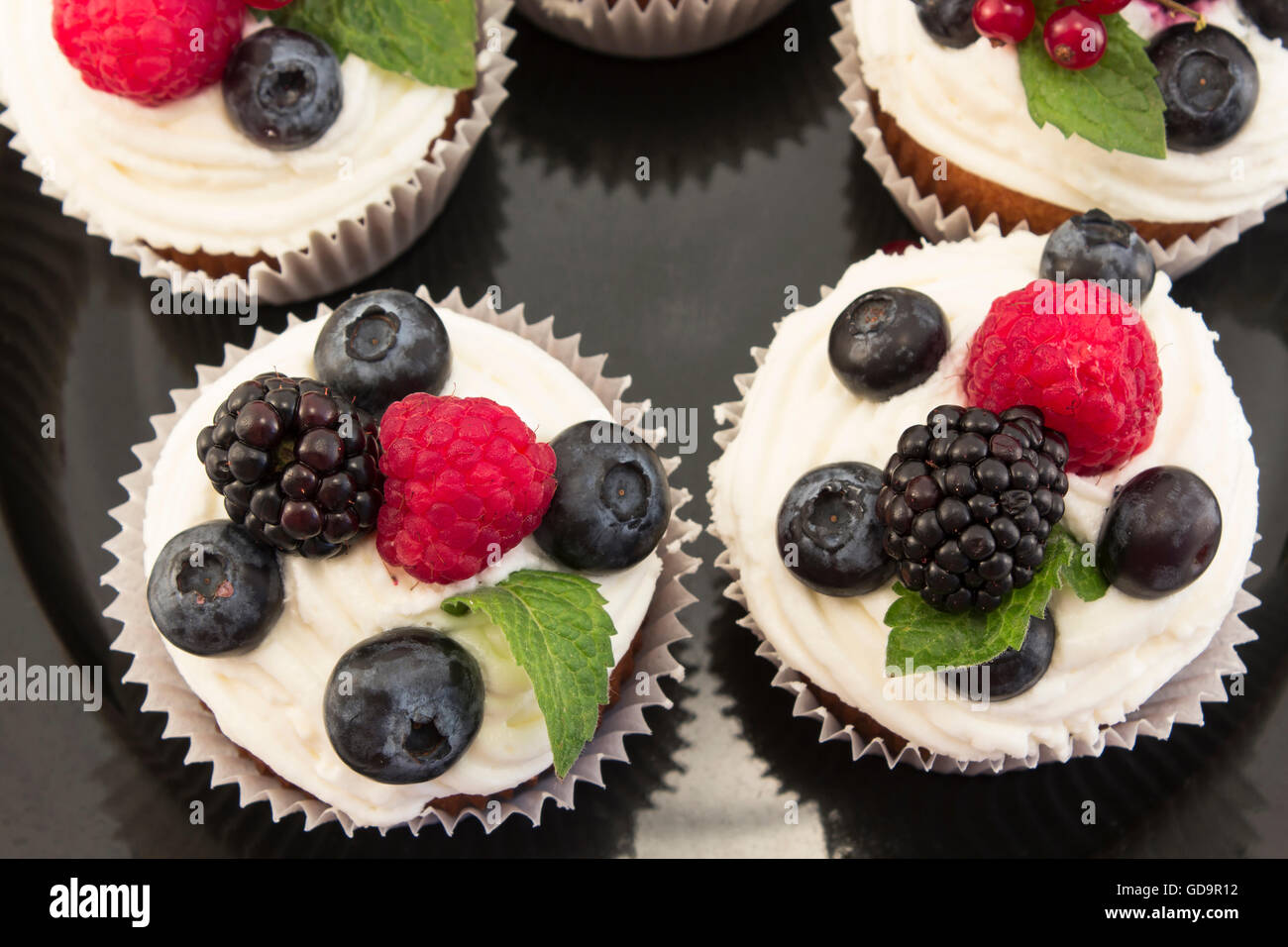 Cupcakes aux fruits rouges élégants sur la plaque noire. Banque D'Images