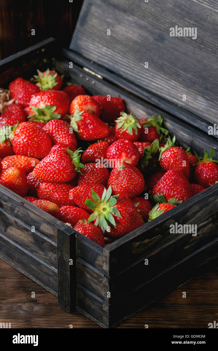 Jus de fraises frais mûrs dans le bois fort sur fond de bois sombre. Banque D'Images