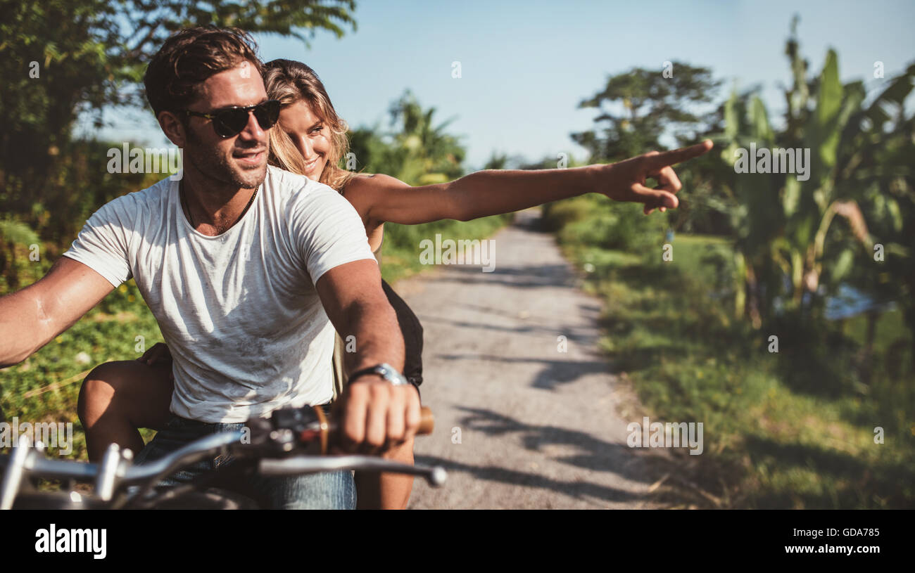 De horizontale équitation moto. L'homme à cheval sur une moto avec ma copine en pointant à l'écart on rural road. Banque D'Images