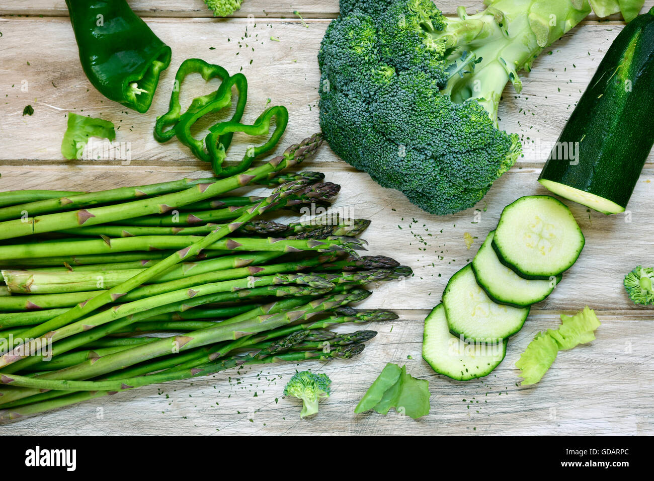 Tourné à angle élevé de certaines matières premières différentes légumes verts, comme le poivron vert, les asperges, le brocoli ou les courgettes, sur un blanc rustique Banque D'Images