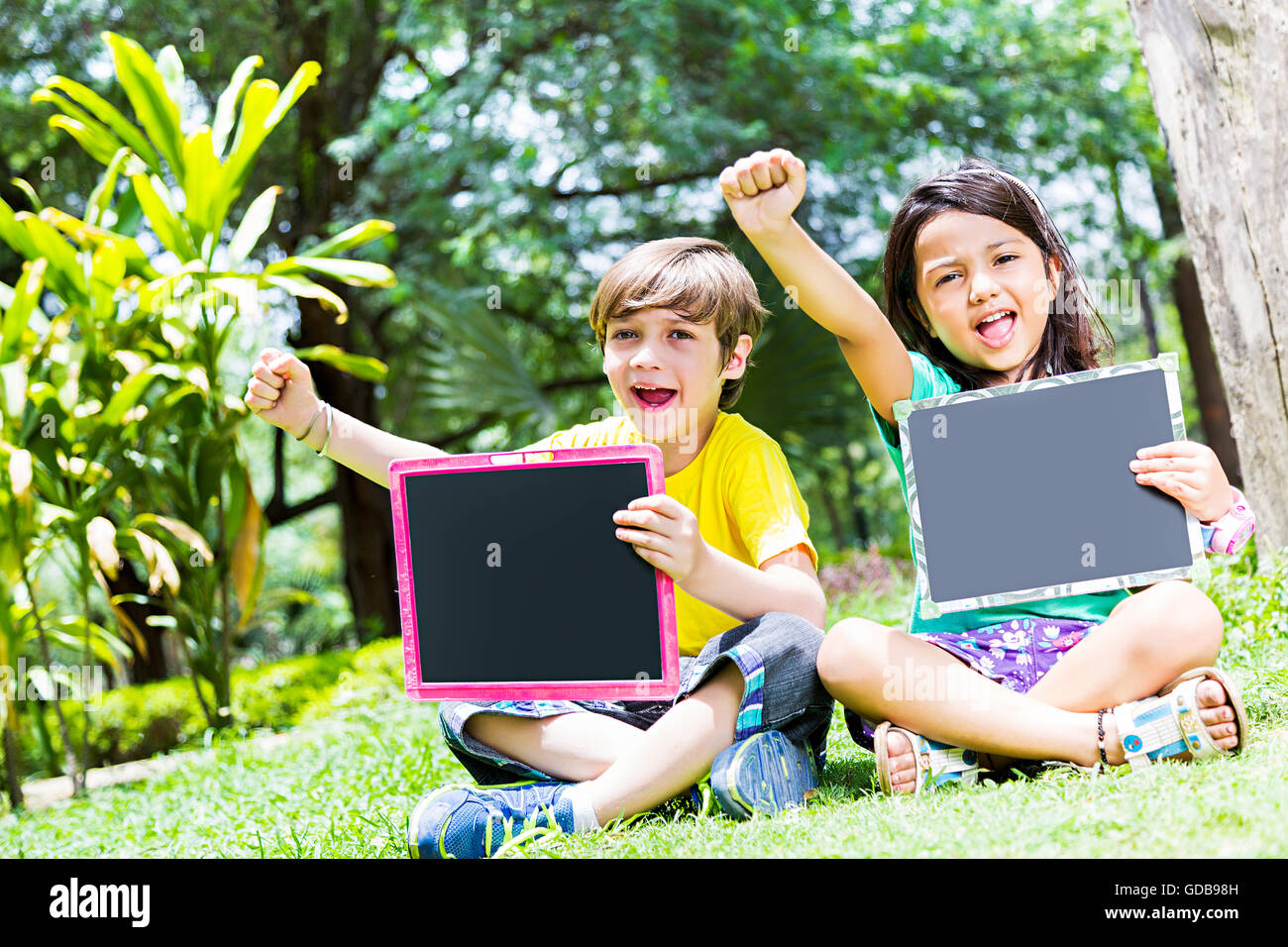 2 enfants fille et garçon indien étudiants amis d'Ardoise parc montrant Banque D'Images