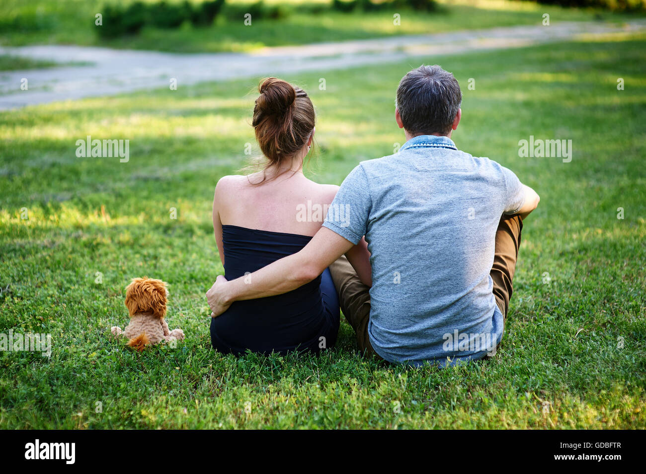 Love couple assis sur l'herbe en été park retour Banque D'Images
