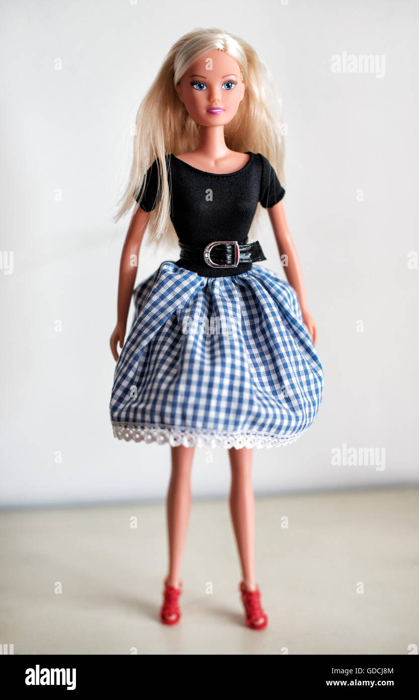 Poupée jouet blonde unique en longueur au genou jupe bleu et blanc à carreaux, chemisier noir et chaussures rouges Banque D'Images