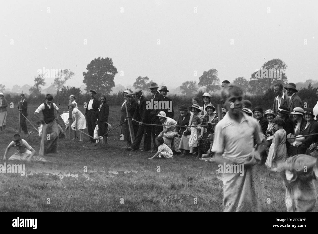 Les garçons dans un sac la race. Les deux garçons et la foule sont clairement profiter de la course. Lieu inconnu c1930. Photographie par Tony Henshaw Banque D'Images