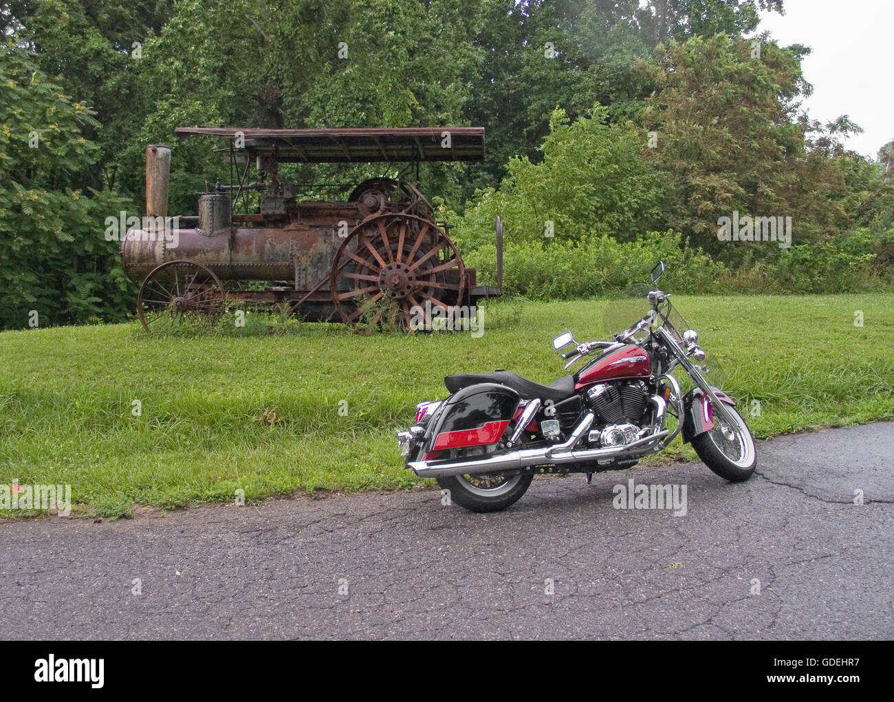 Une moto garée près d'un vieux tracteur agricole rouillé, à proximité de la Blue Ridge Parkway en Virginie, USA un jour d'été. Banque D'Images