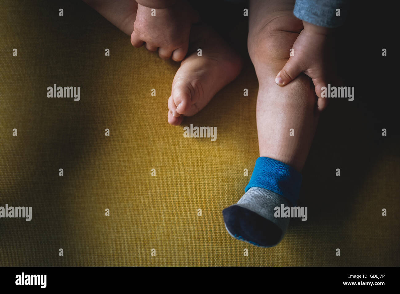 Les jambes du bébé garçon sur chaise jaune Banque D'Images