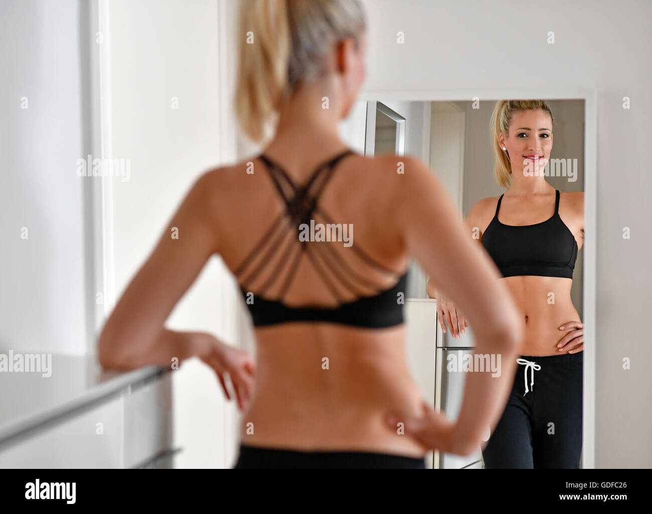 Jeune femme avec soutien-gorge de sport et de jogging se regarde dans le miroir Banque D'Images