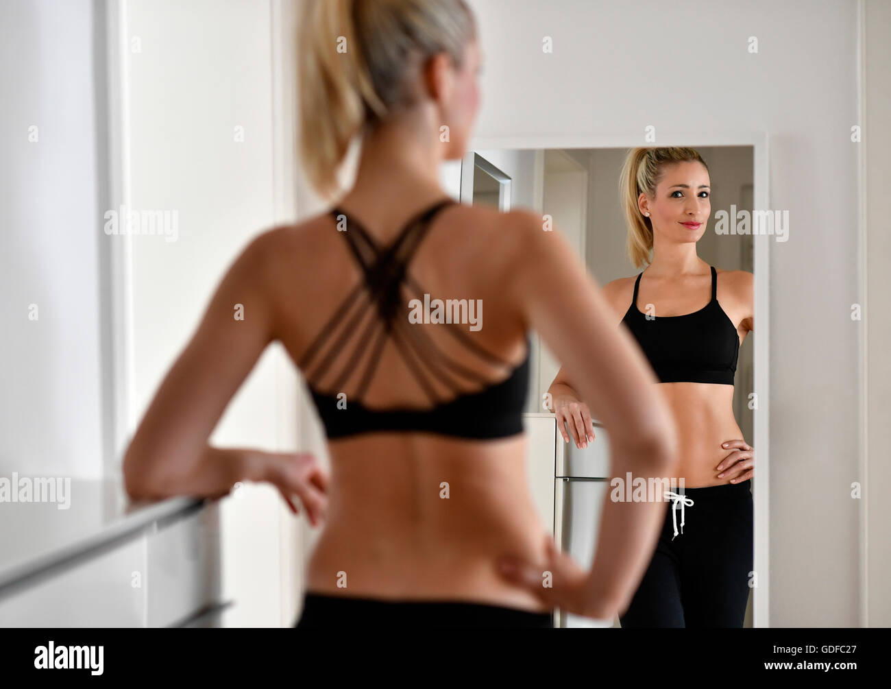 Jeune femme avec soutien-gorge de sport et de jogging se regarde dans le miroir Banque D'Images