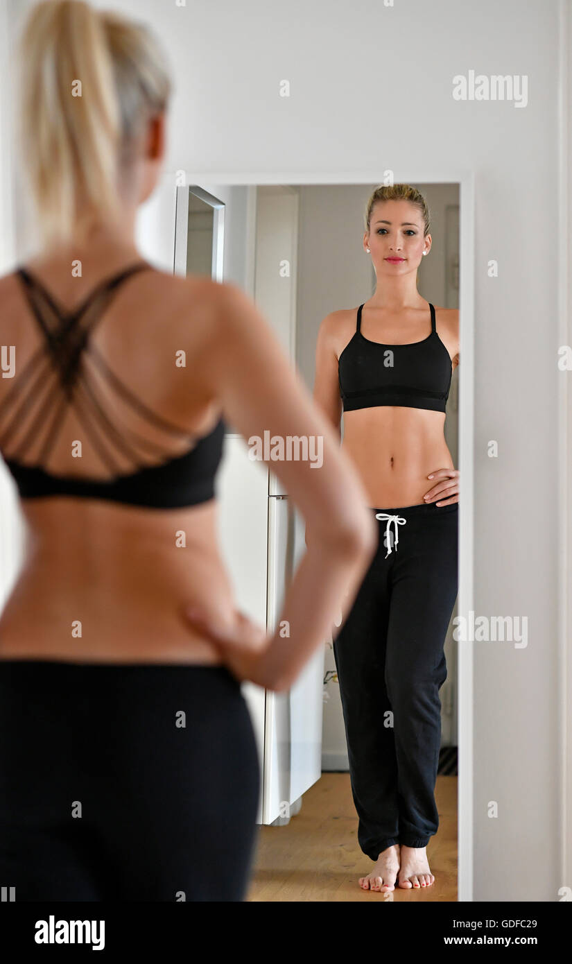 Jeune femme avec soutien-gorge de sport et de jogging se regarde dans le miroir Banque D'Images