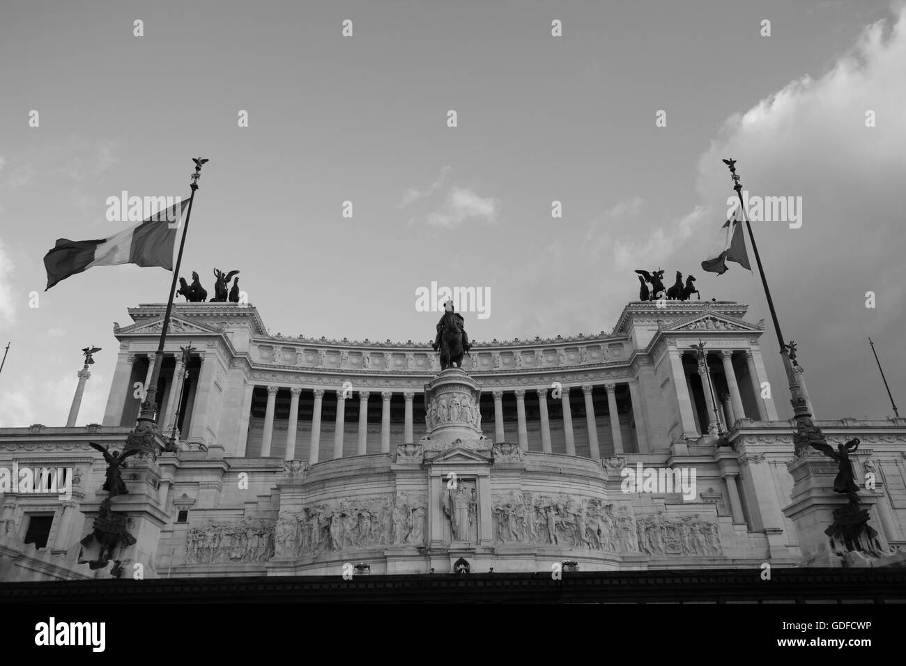 Altare della Patria, hommage monumental de Rome à l’unité et à la nation, capturé en noir et blanc saisissant avec des drapeaux hissés sous un ciel spectaculaire. Banque D'Images
