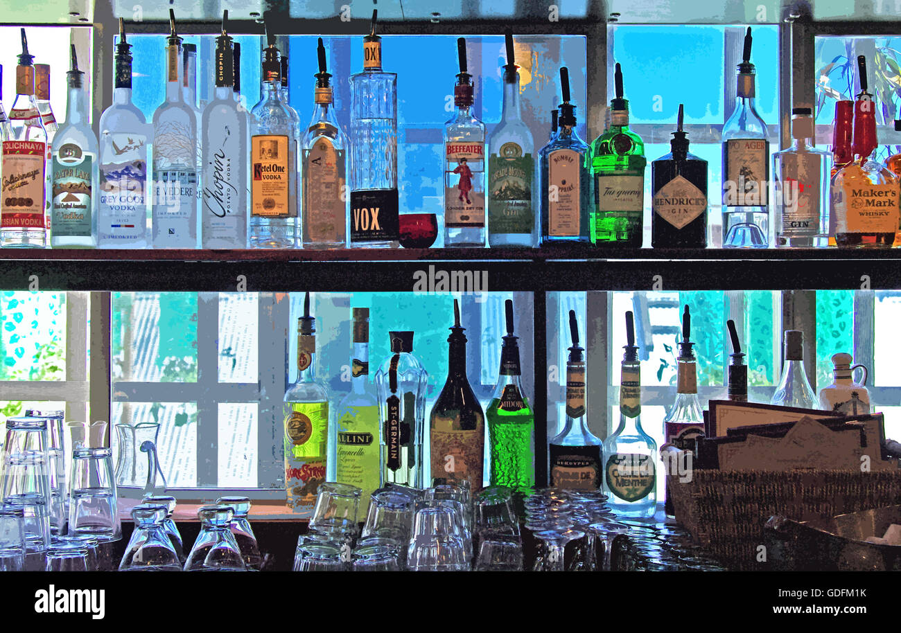 Des bouteilles de boissons et de liqueurs pour adultes aux couleurs vives, avec cocktails et verres à vin empilés, sont placées sur une étagère dans un salon haut de gamme. Banque D'Images