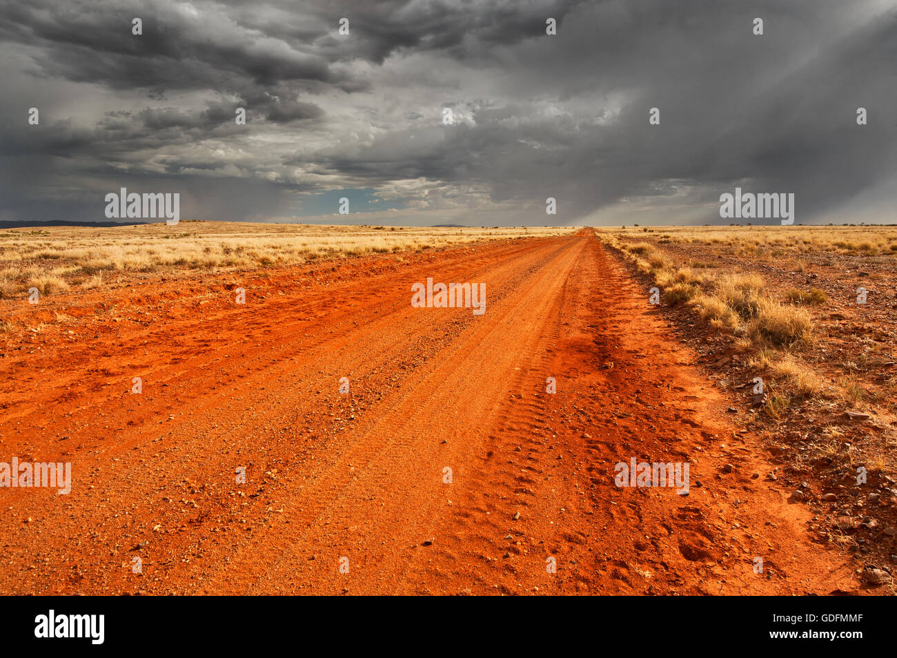 Des nuages sombres qui arrive sur une piste du désert. Banque D'Images