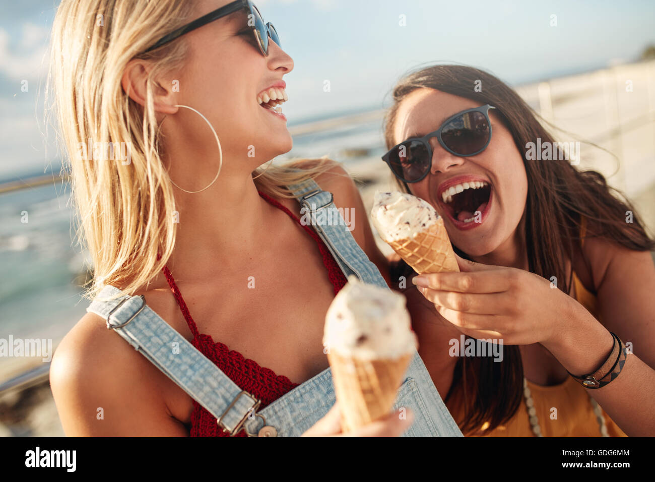 Deux meilleurs amis, pour avoir ensemble la crème glacée à l'extérieur. Close up of young women eating icecream et rire. Banque D'Images
