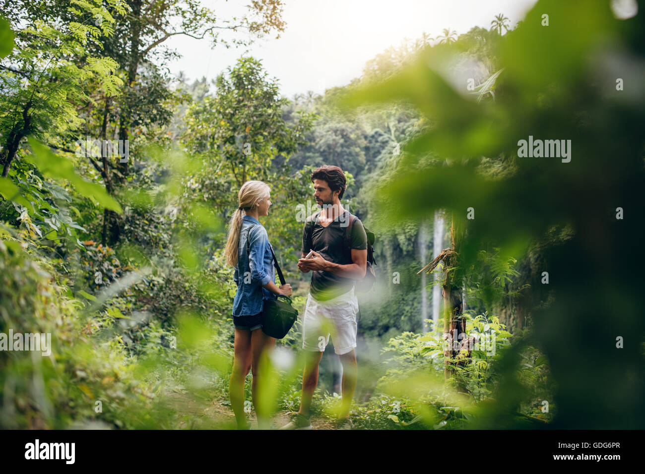 Tourné en plein air de jeune homme et femme debout ensemble sur une falaise et parler. Couple de randonneurs ensemble dans une forêt avec de l'eau f Banque D'Images