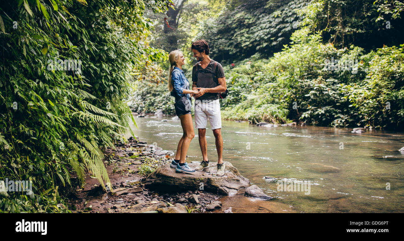 Jeune couple aimant par un ruisseau de montagne dans la forêt. Deux randonneurs par flux en bois. Banque D'Images
