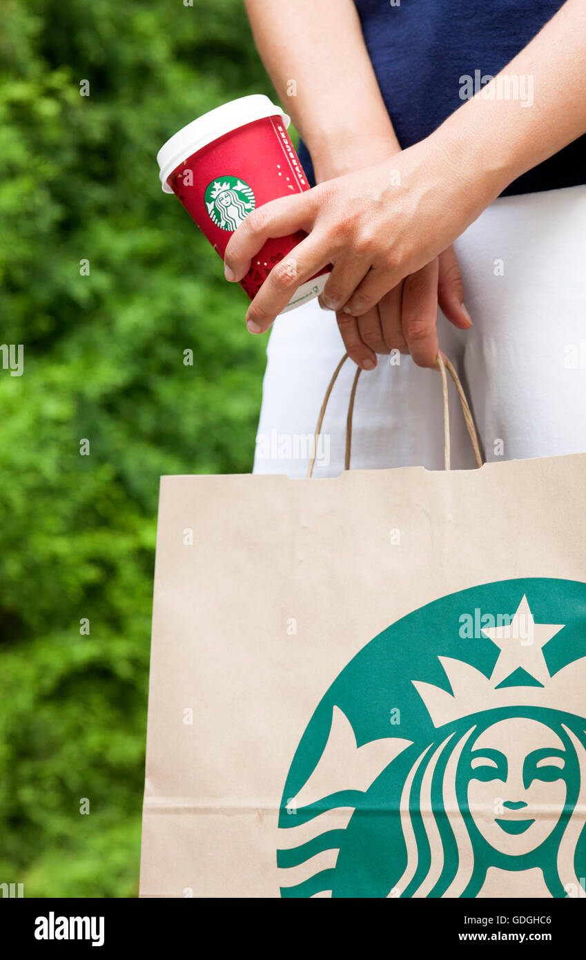 Paphos, Chypre - 23 novembre, 2013 Femme en rue avec des plats à emporter Starbucks sac en papier et papier rouge tasse de café dans ses mains. Banque D'Images